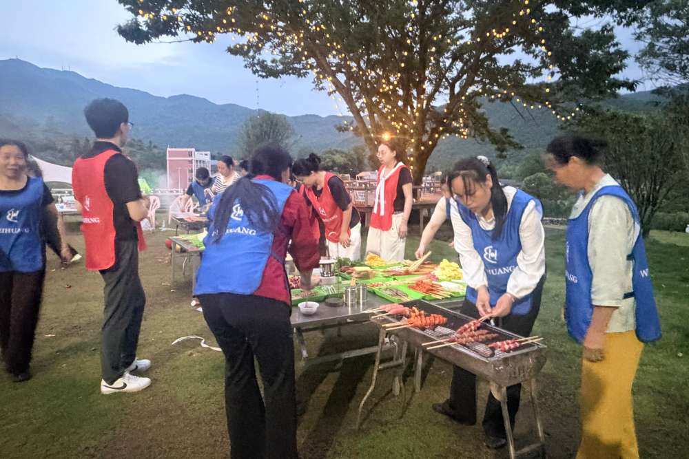 Weihuang Textile full team photo with mountain backdrop and company banner