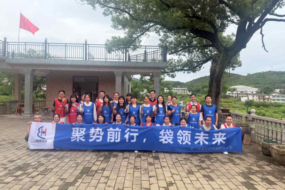Weihuang Textile team building group photo with banner Gathering Momentum Weaving the Future
