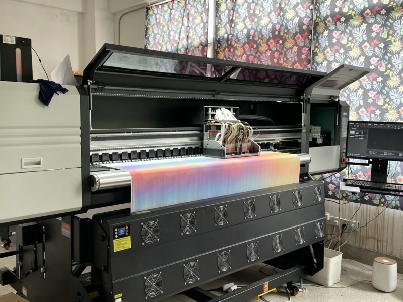 Digital printing closeup showing industrial inkjet printhead applying full color design onto fabric